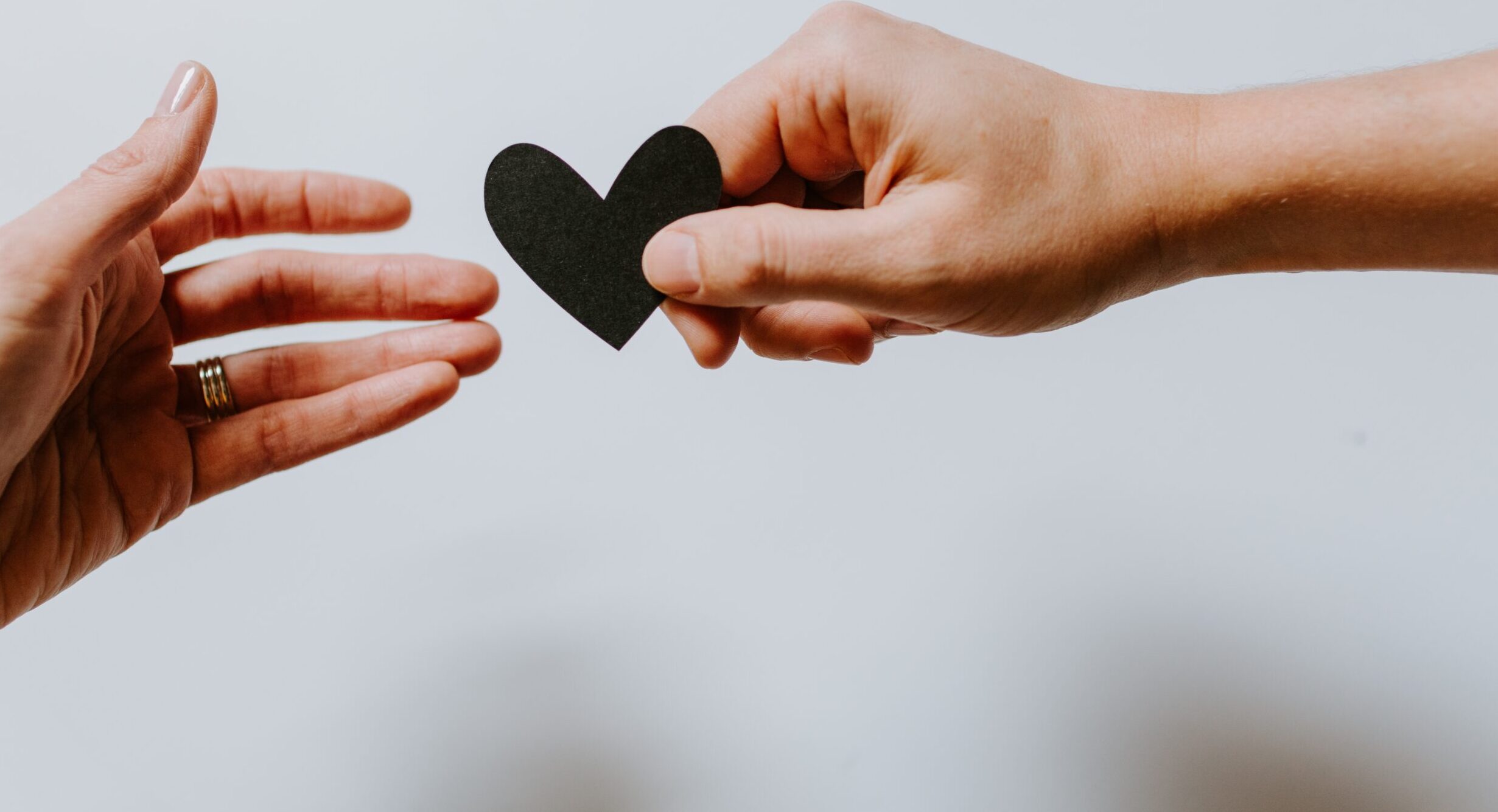 person reaching black heart cutout paper